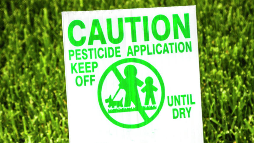 Caution sign on a lawn sprayed with pesticide